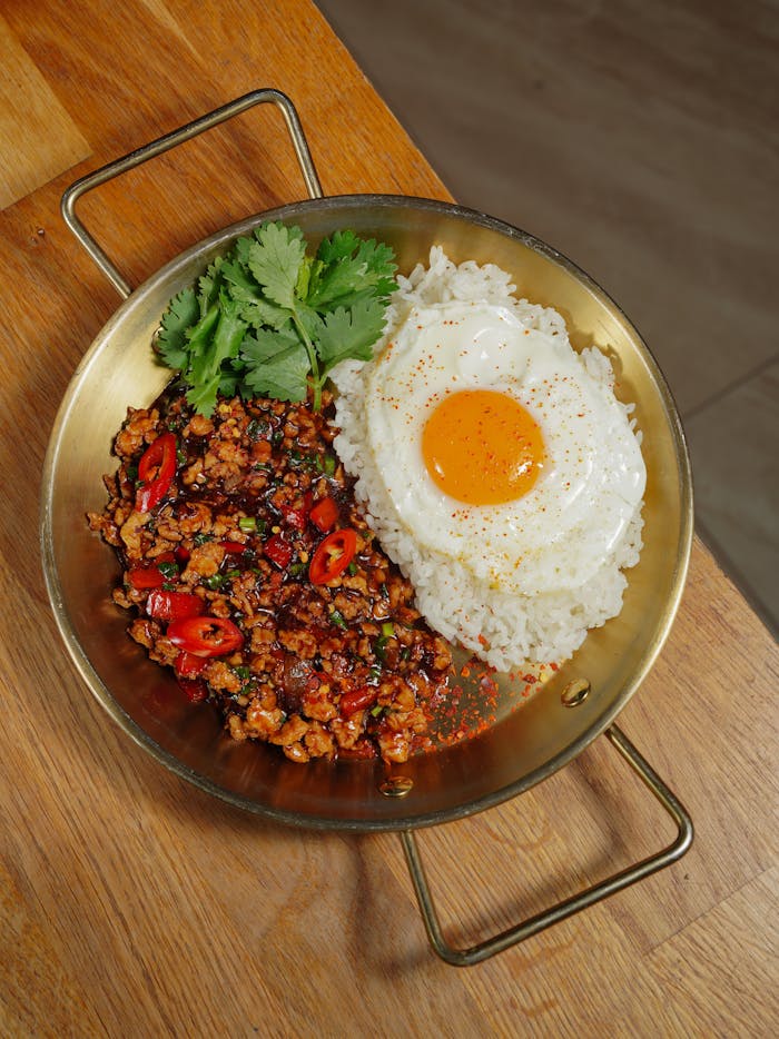 Appetizing Thai basil chicken served with rice and a perfectly cooked fried egg.