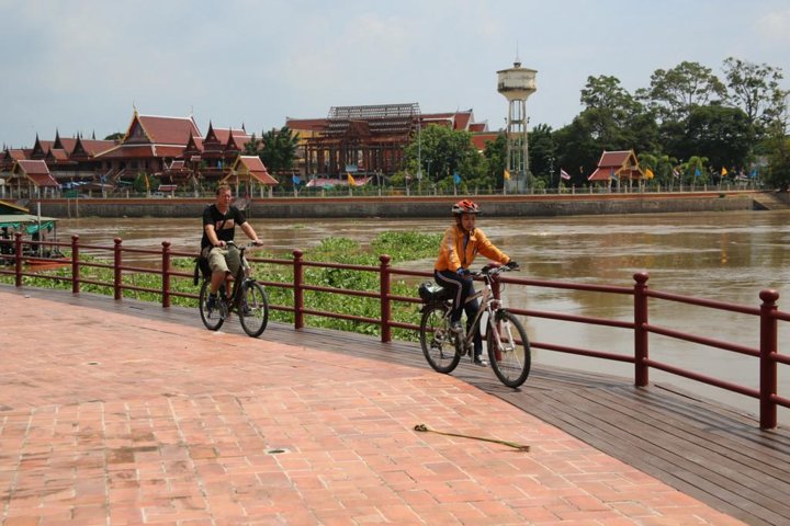 Cyclists riding along the river path in Ayutthaya